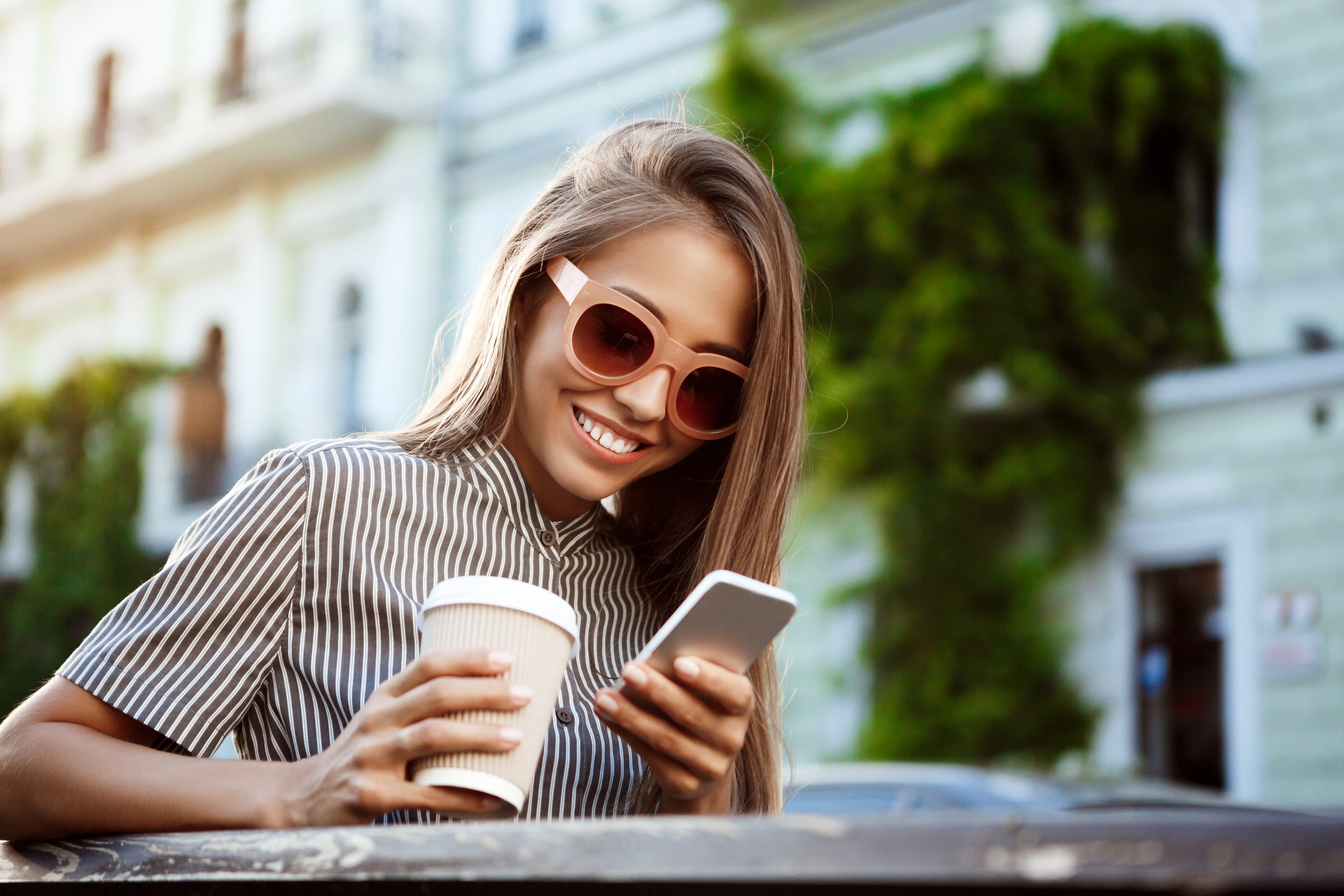 Smiling woman sitting at table in evening, looking at her phone with digital menu